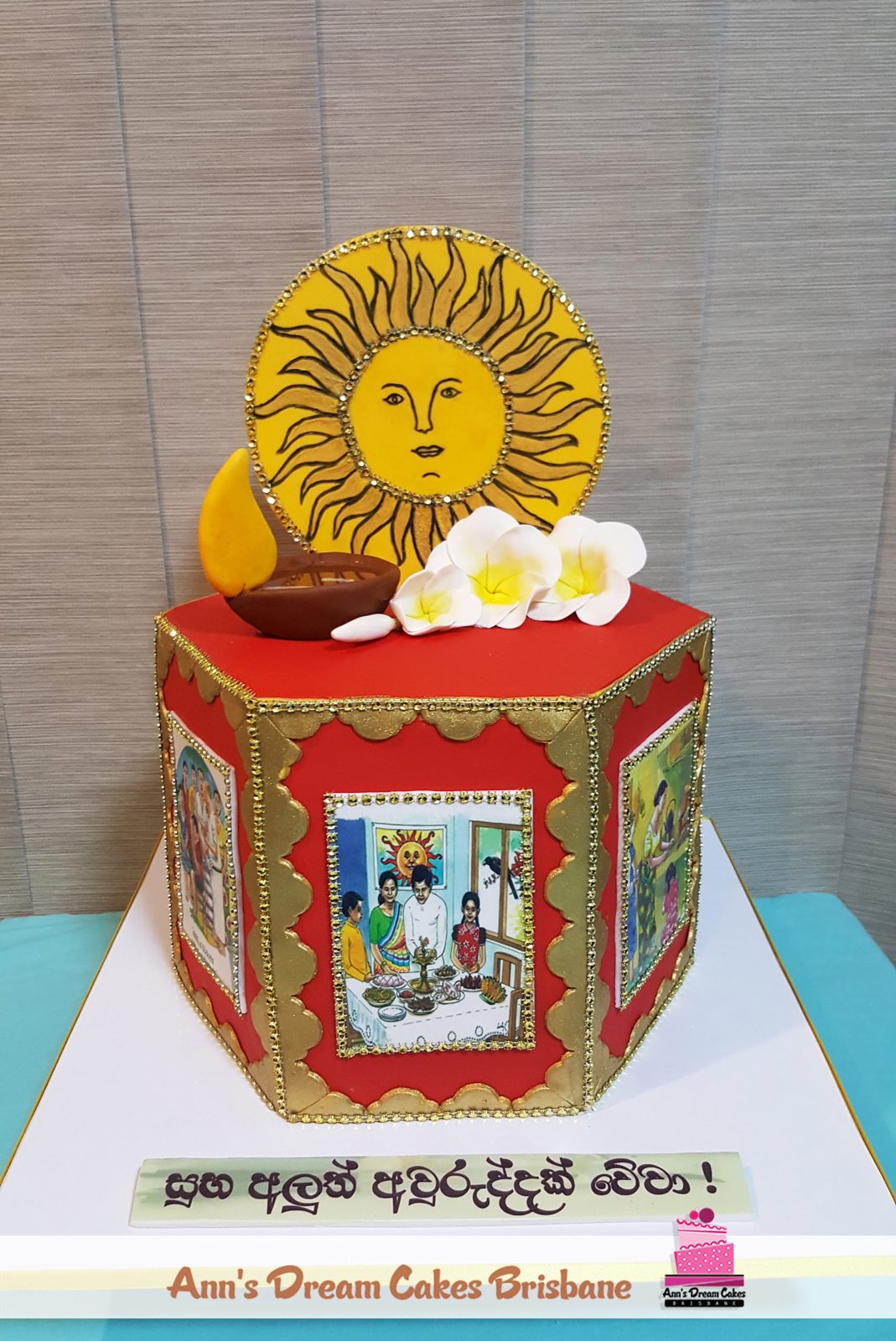 Red and gold hexagonal New Year cake with a hand painted sun topper and sugar flowers