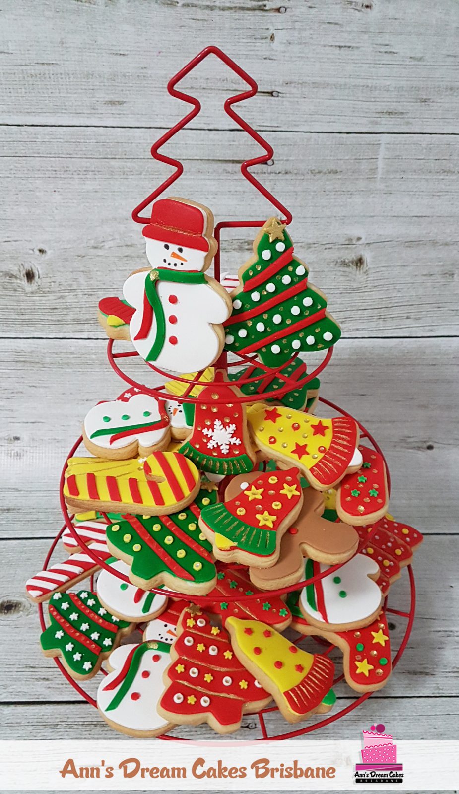 Three tier stand of iced Christmas sugar cookies shaped as snowmen, trees, stockings and gingerbread men
