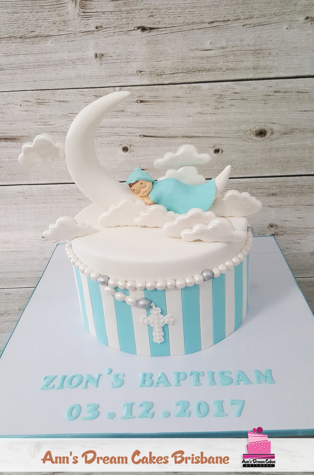 White and pale blue christening cake with a sleeping fondant baby on a crescent moon
