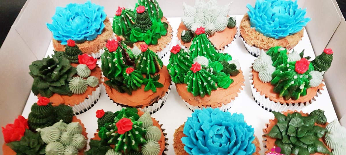 A box of twelve cupcakes piped in buttercream as succulents and cacti